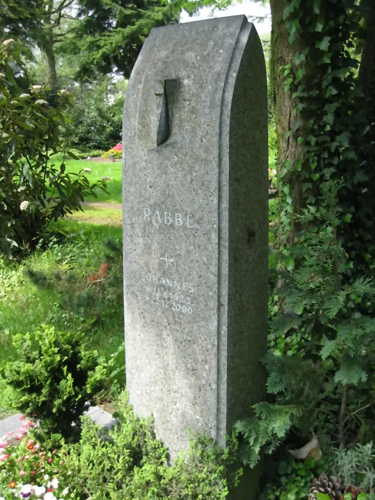 Hohe Grabstele aus grau-grünem Granit mit ausgearbeiteter Nische und eingelassenem Kreuz