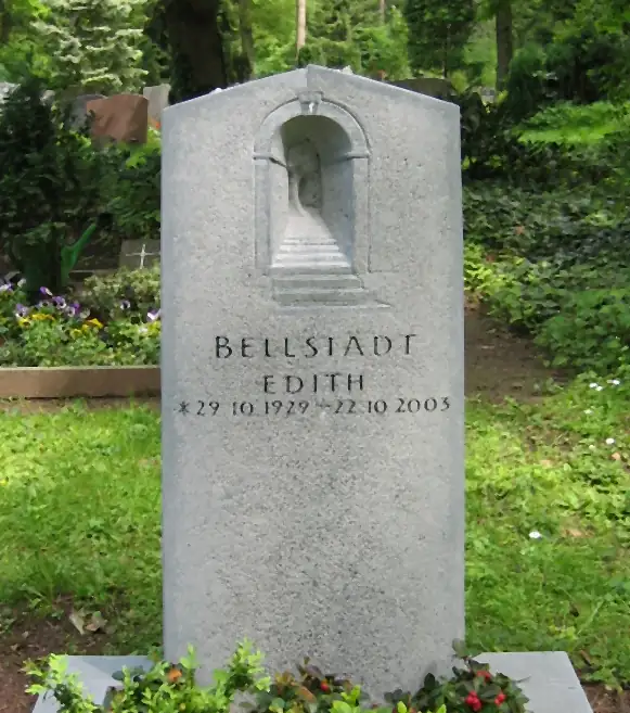 Helle Grabstele mit reliefiertem Torbogen und eingehauener Schrift