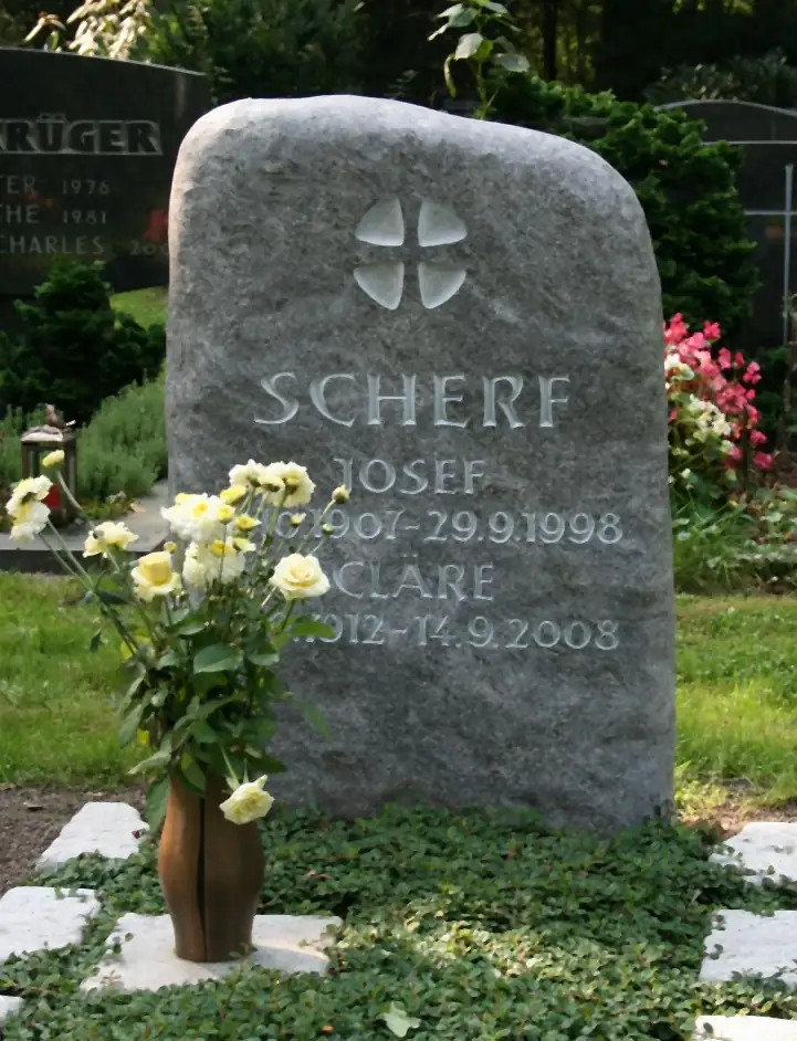 Grabmal aus grauem Granit mit reliefiertem Kreuz und eingehauener Schrift