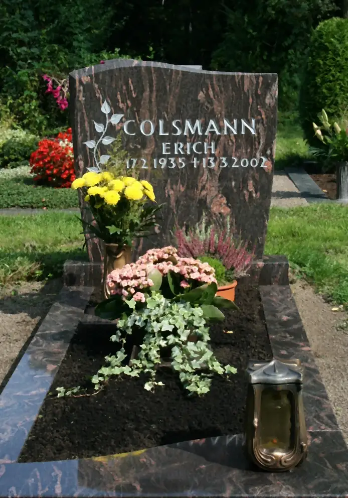 Grabanlage aus rotbraunem Granit mit Blattornament, Einfassung und Bepflanzung